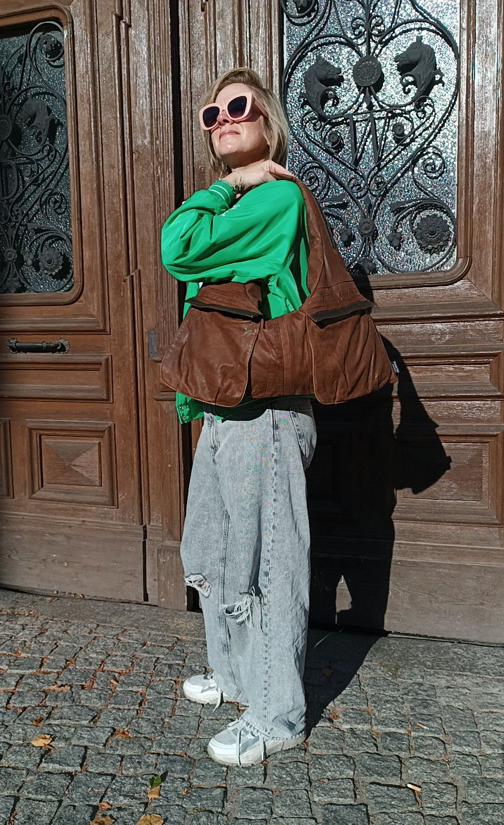 Person trägt die Triangle Bag S aus braun mattem Leder von wallawalla Berlin als Schultertasche zu einem lässigen Outfit.