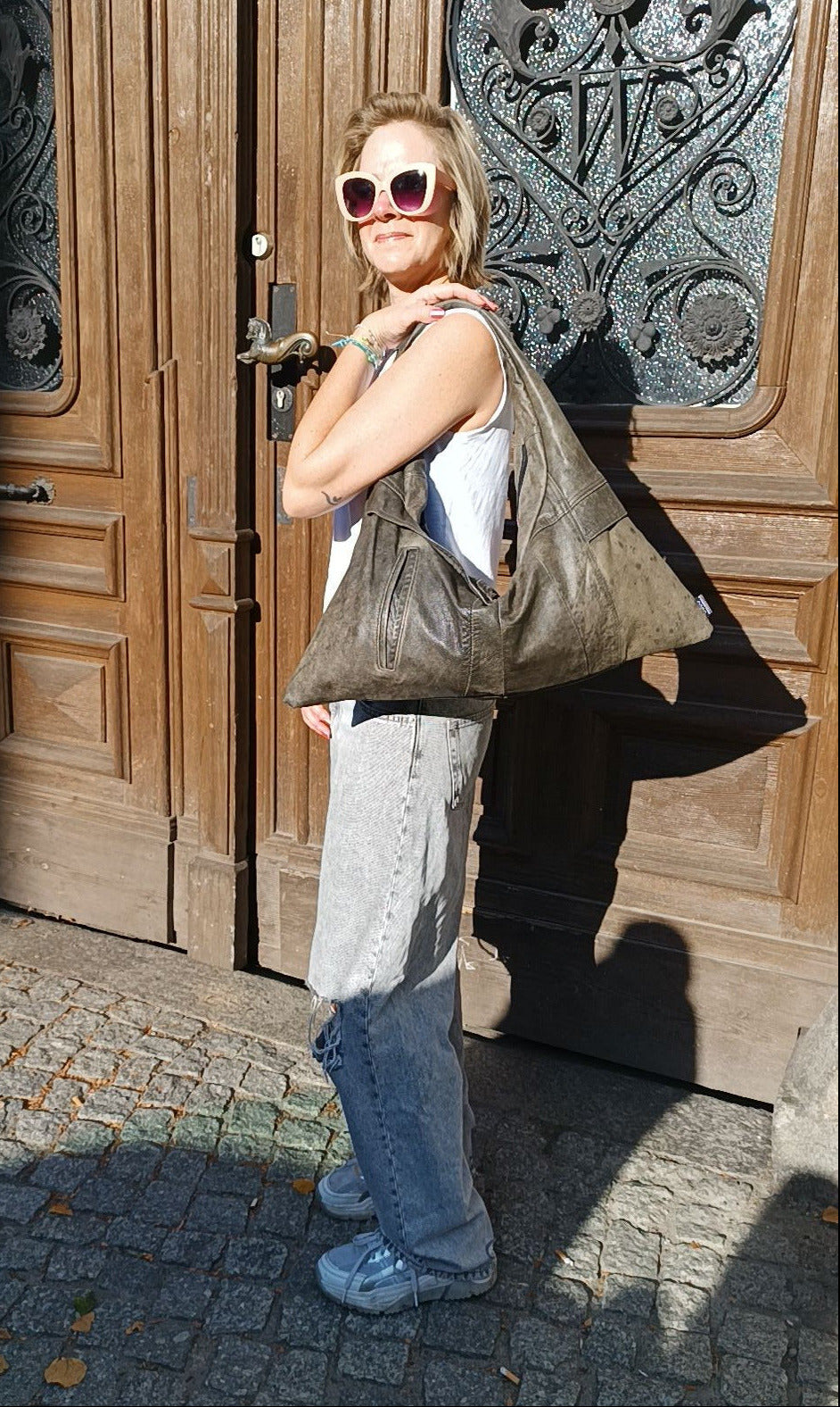 Frau trägt die Triangle Bag S aus Vintage-Leder von wallawalla Berlin als Schultertasche zu einem lässigen Outfit.