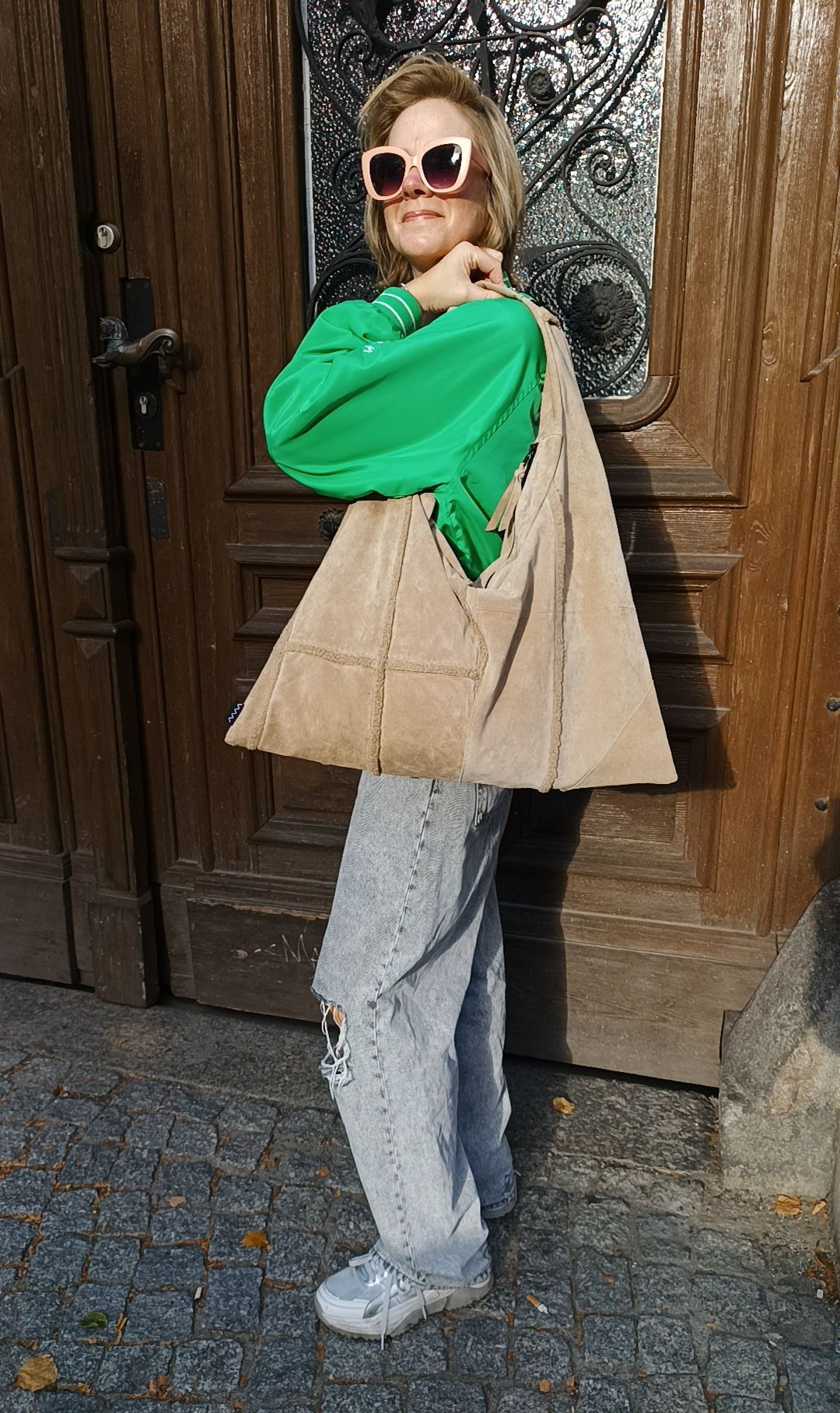 Frau trägt die Triangle Bag L aus beigem Wildleder von wallawalla Berlin als Schultertasche zu einem lässigen Outfit.