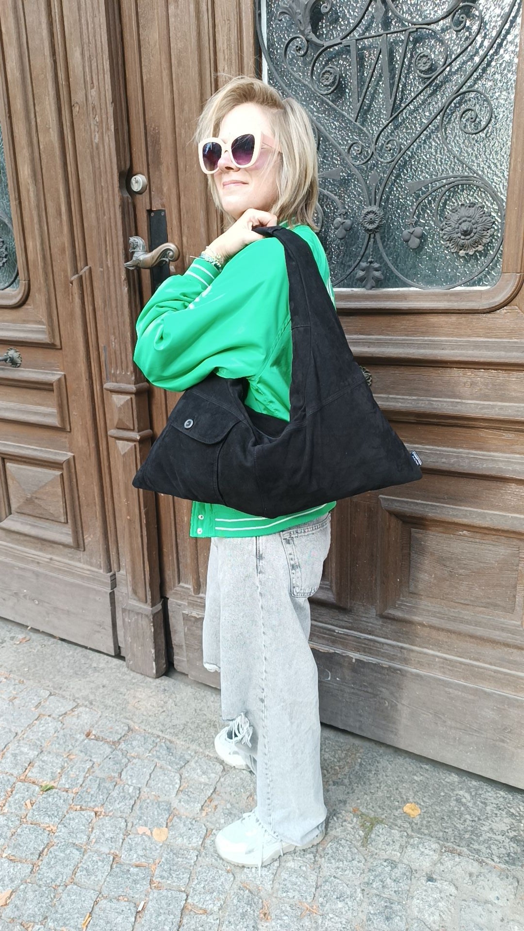 Person trägt die Triangle Bag S aus schwarzem Wildleder von wallawalla Berlin als Schultertasche zu einem lässigen Outfit.